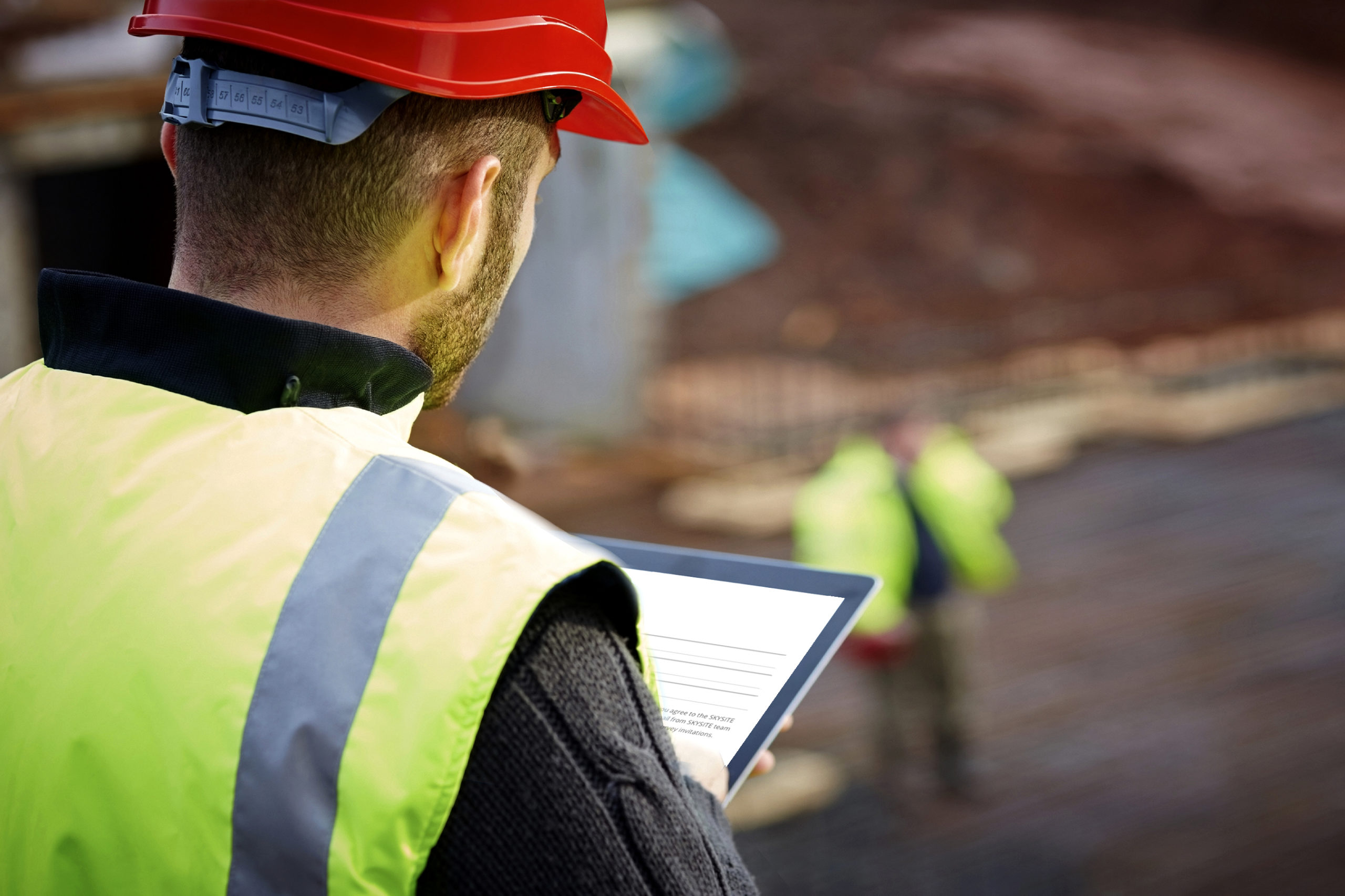 Rear view of male construction worker working with digital tablet on construction site